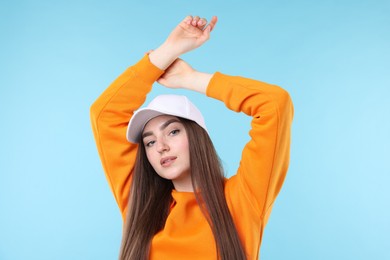 Photo of Portrait of beautiful woman in stylish baseball hat on light blue background