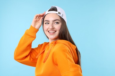 Photo of Smiling woman in stylish baseball hat on light blue background