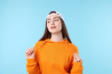 Photo of Portrait of beautiful woman in stylish baseball hat on light blue background