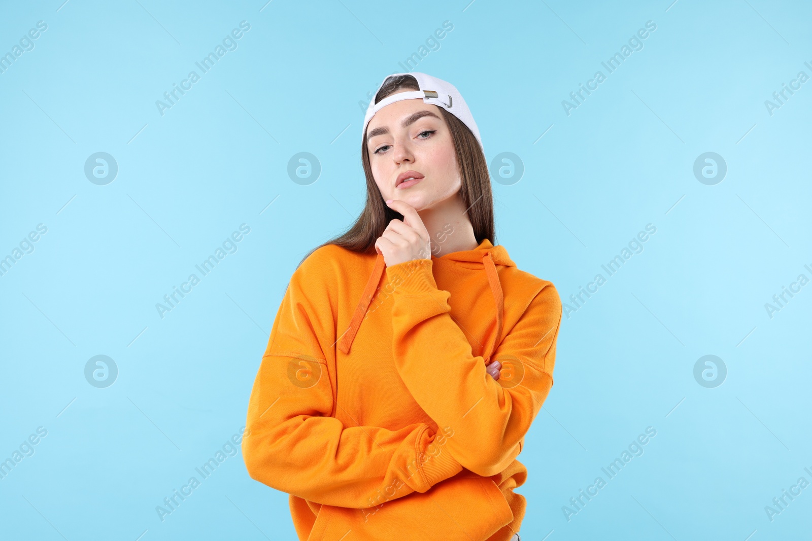 Portrait of beautiful woman in stylish baseball hat on light blue background Photo of Portrait of beautiful woman in stylish baseball hat on light blue background