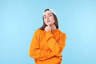 Photo of Portrait of beautiful woman in stylish baseball hat on light blue background