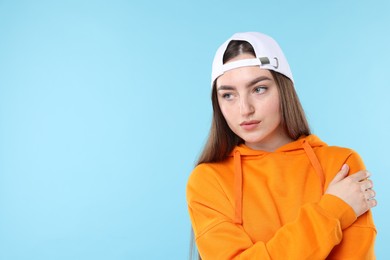 Photo of Beautiful woman in stylish baseball hat on light blue background. Space for text