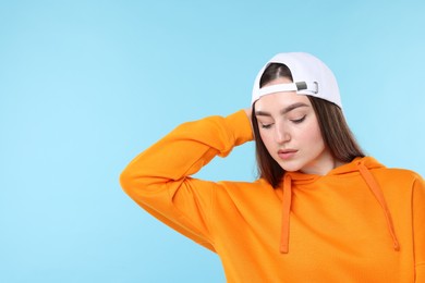 Photo of Beautiful woman in stylish baseball hat on light blue background. Space for text