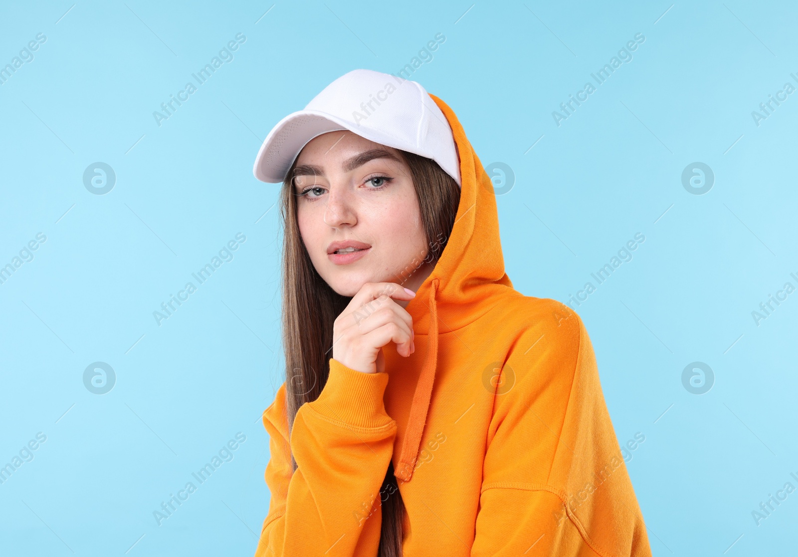 Portrait of beautiful woman in stylish baseball hat on light blue background Photo of Portrait of beautiful woman in stylish baseball hat on light blue background