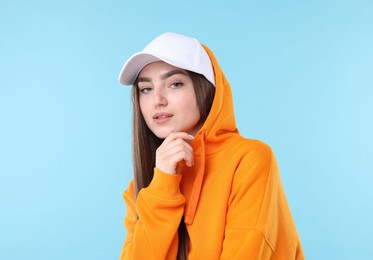 Photo of Portrait of beautiful woman in stylish baseball hat on light blue background