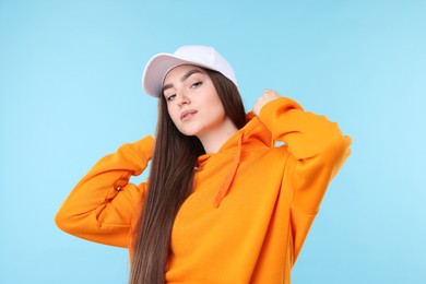 Photo of Portrait of beautiful woman in stylish baseball hat on light blue background