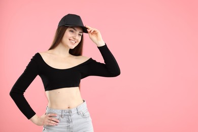 Photo of Smiling woman in stylish baseball hat on pink background. Space for text