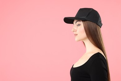 Photo of Beautiful woman in stylish baseball hat on pink background. Space for text