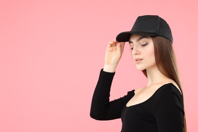 Photo of Beautiful woman in stylish baseball hat on pink background. Space for text