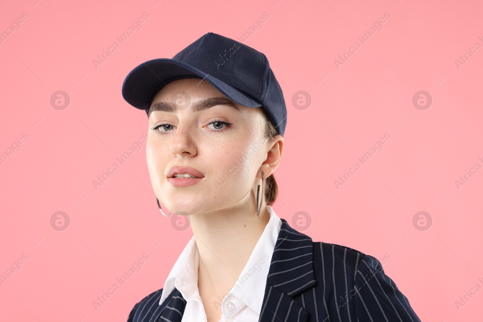 Portrait of beautiful woman in stylish baseball hat on pink background, closeup Photo of Portrait of beautiful woman in stylish baseball hat on pink background, closeup