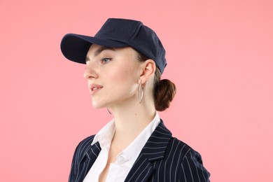 Photo of Beautiful woman in stylish baseball hat on pink background