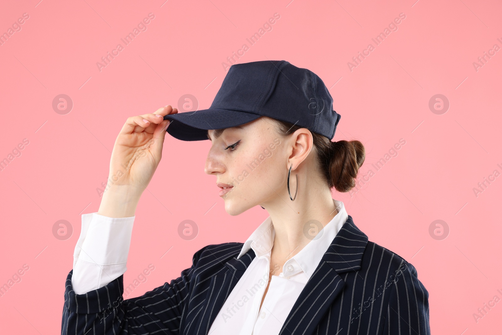 Beautiful woman in stylish baseball hat on pink background Photo of Beautiful woman in stylish baseball hat on pink background