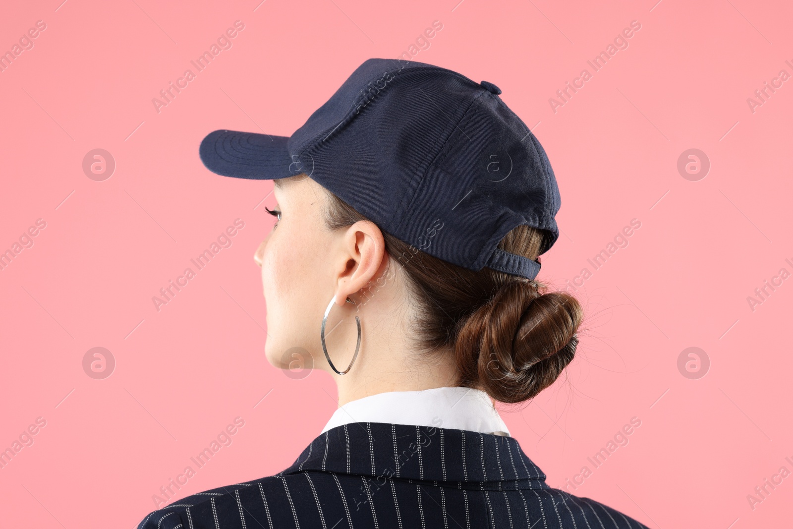 Woman in stylish baseball hat on pink background Photo of Woman in stylish baseball hat on pink background
