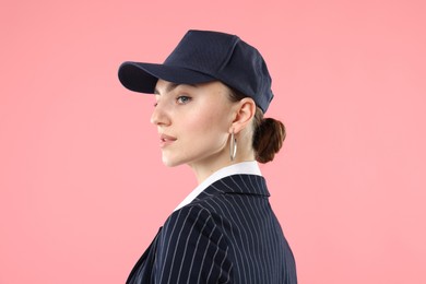 Photo of Beautiful woman in stylish baseball hat on pink background