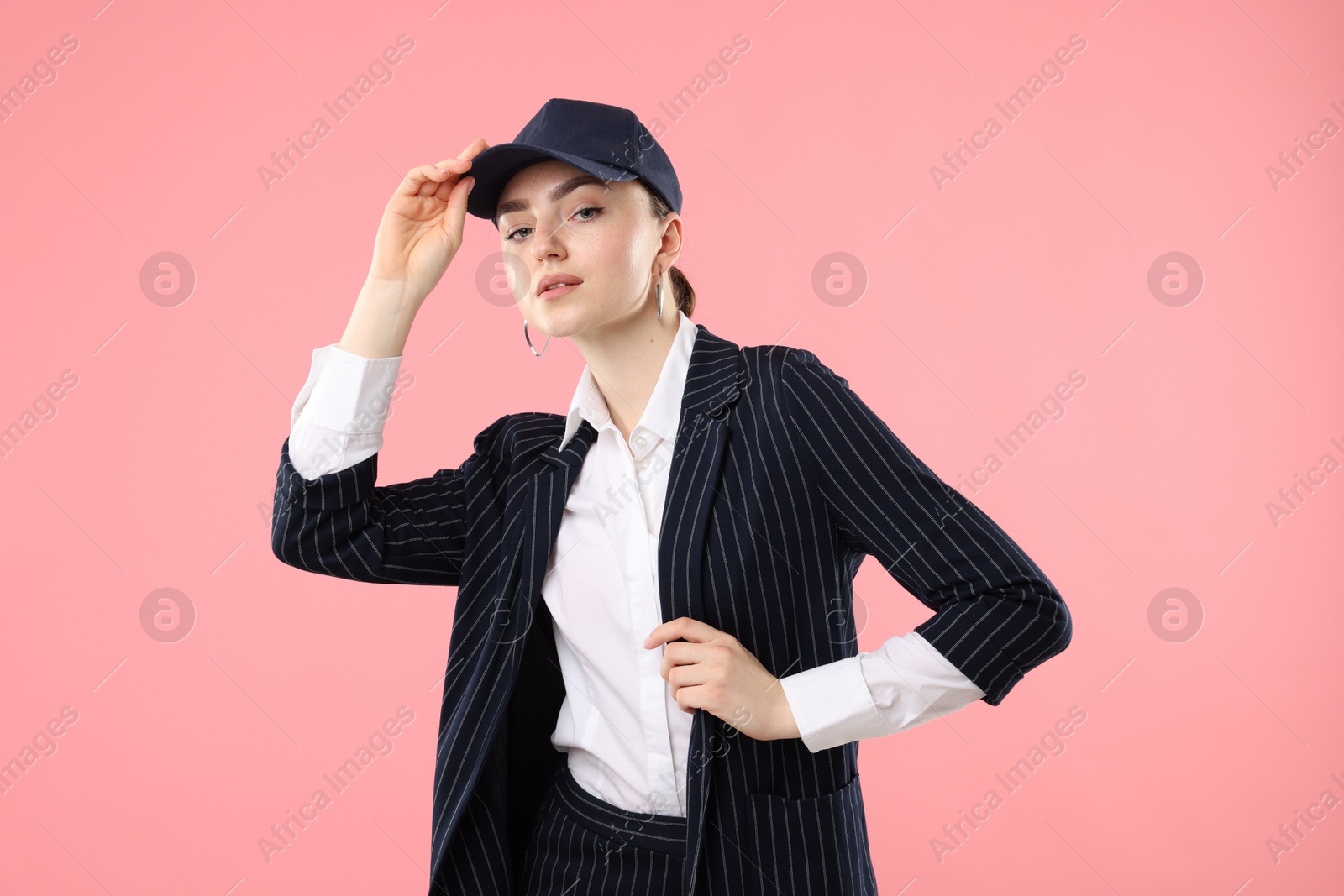 Portrait of beautiful woman in stylish baseball hat on pink background Photo of Portrait of beautiful woman in stylish baseball hat on pink background