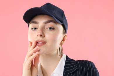 Photo of Portrait of beautiful woman in stylish baseball hat on pink background, closeup
