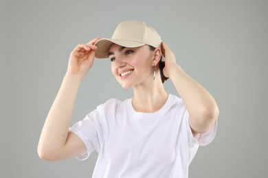 Photo of Smiling woman in stylish baseball hat on grey background