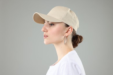 Photo of Beautiful woman in stylish baseball hat on grey background, closeup