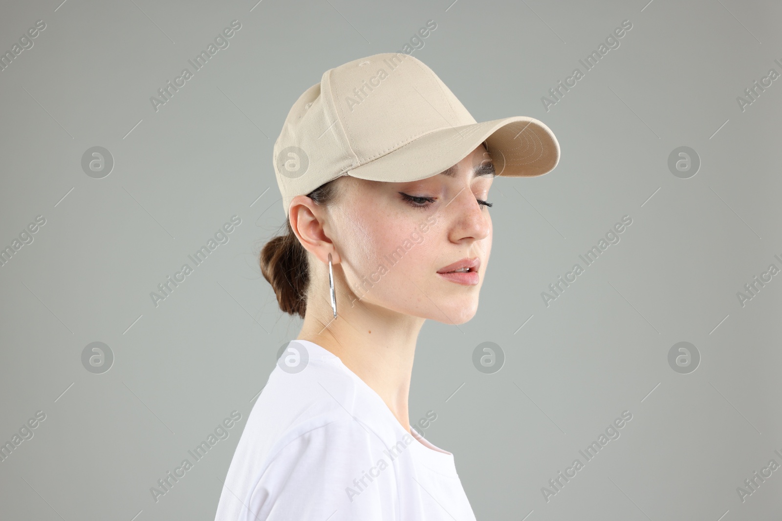 Beautiful woman in stylish baseball hat on grey background, closeup Photo of Beautiful woman in stylish baseball hat on grey background, closeup