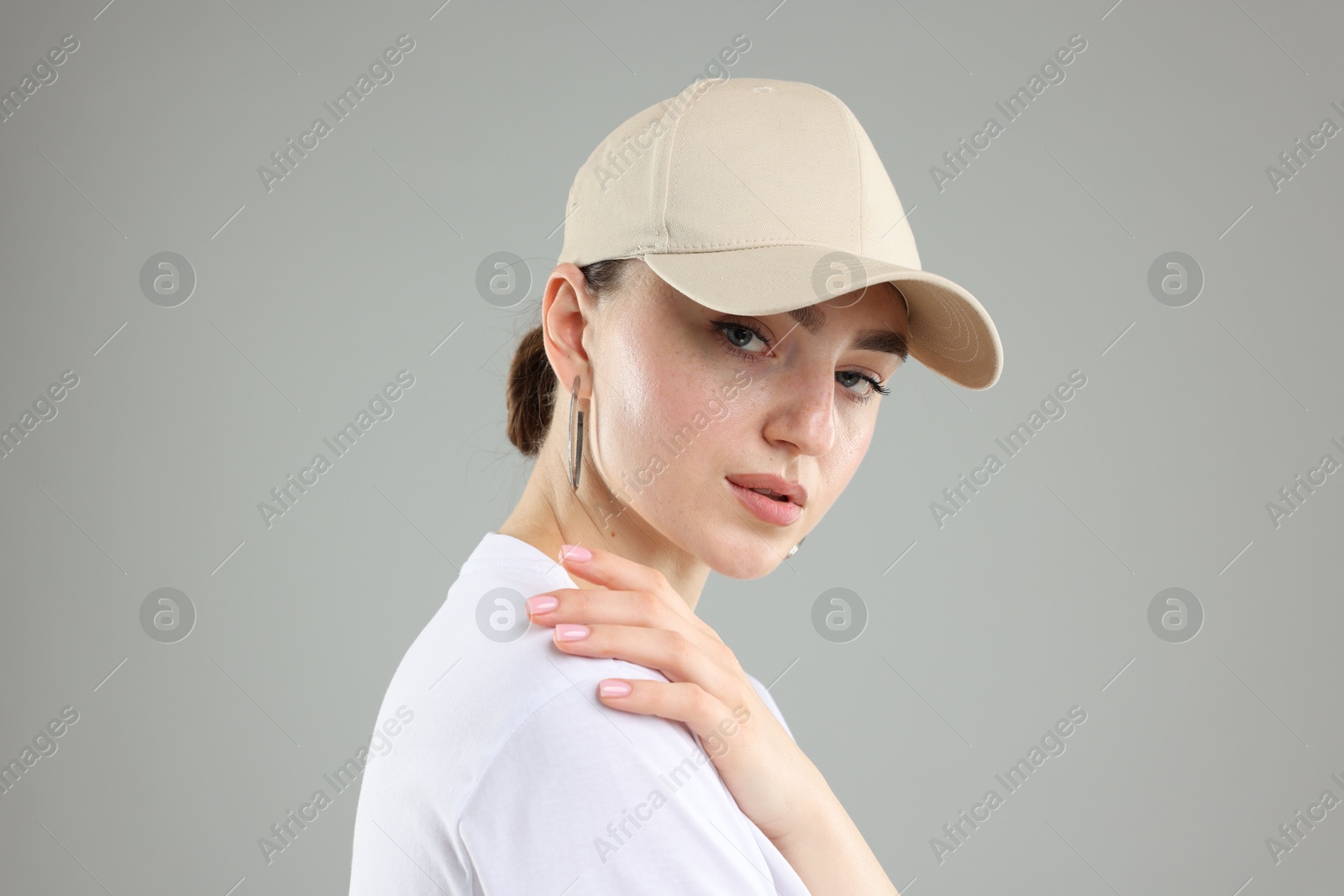 Beautiful woman in stylish baseball hat on grey background, closeup Photo of Beautiful woman in stylish baseball hat on grey background, closeup