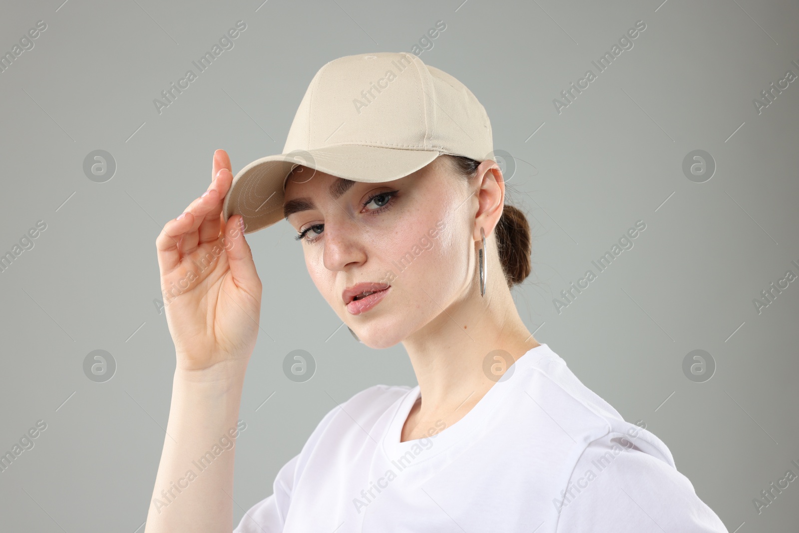 Beautiful woman in stylish baseball hat on grey background, closeup Photo of Beautiful woman in stylish baseball hat on grey background, closeup