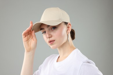 Photo of Beautiful woman in stylish baseball hat on grey background, closeup