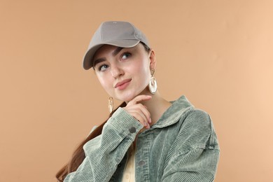 Photo of Beautiful woman in stylish baseball hat on beige background