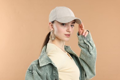 Photo of Portrait of beautiful woman in stylish baseball hat on beige background