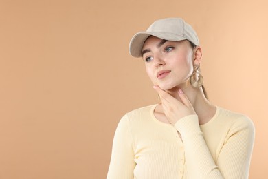 Photo of Beautiful woman in stylish baseball hat on beige background. Space for text