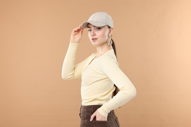 Photo of Portrait of beautiful woman in stylish baseball hat on beige background