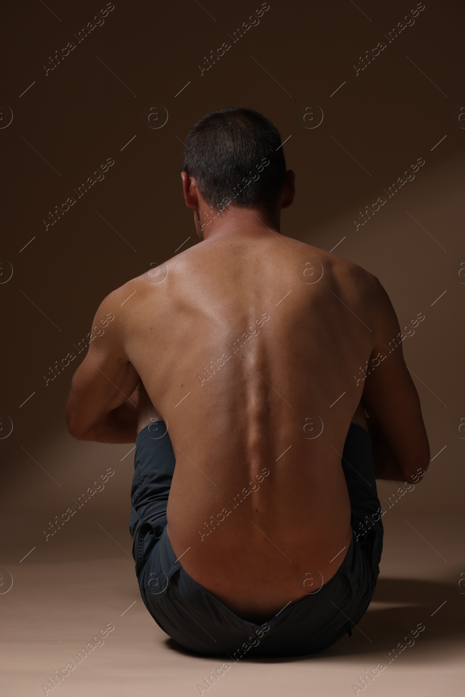 Man suffering from anorexia on beige background, back view Photo of Man suffering from anorexia on beige background, back view