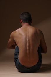 Photo of Man suffering from anorexia on beige background, back view