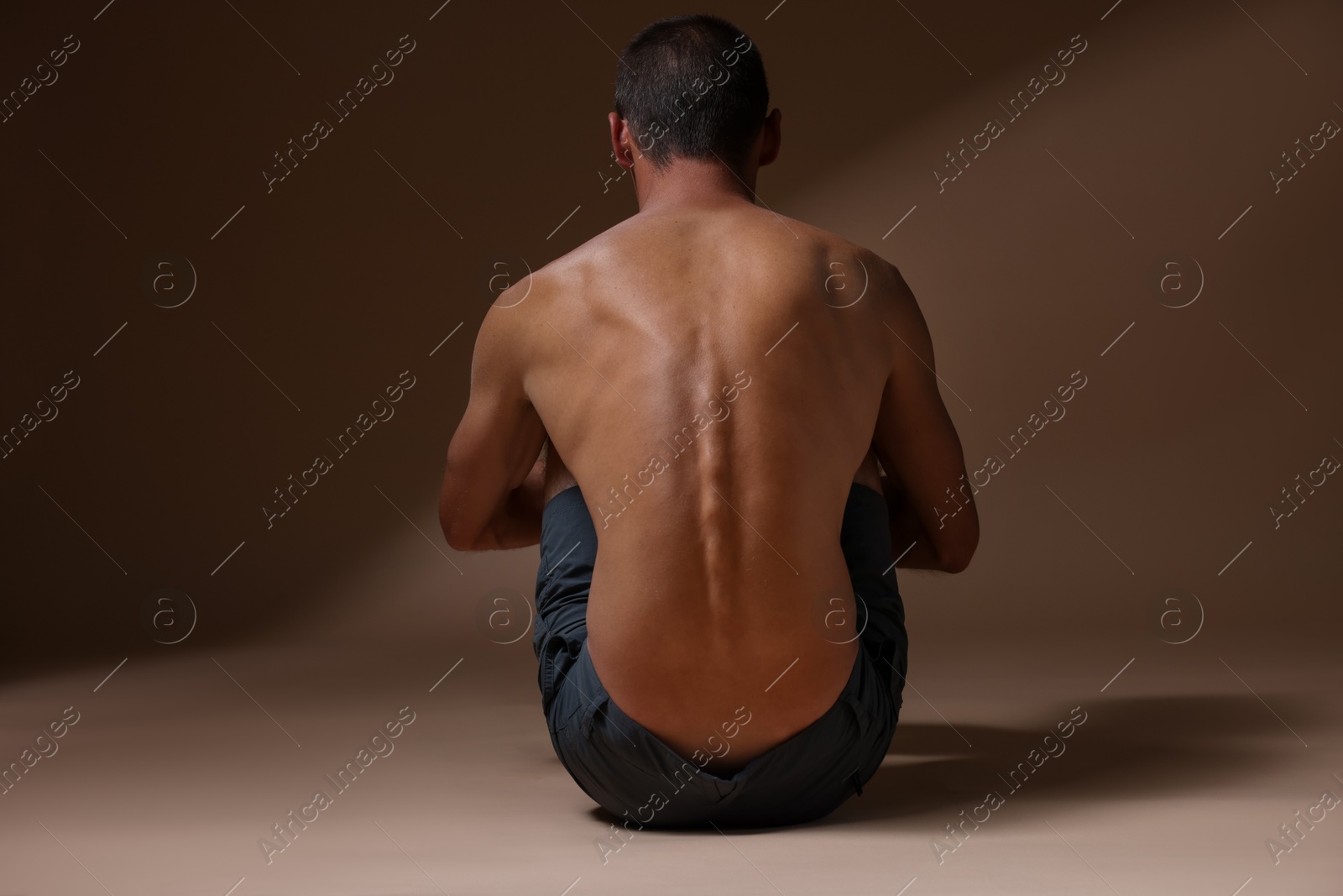 Man suffering from anorexia on beige background, back view Photo of Man suffering from anorexia on beige background, back view