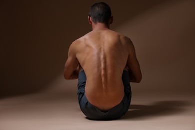 Photo of Man suffering from anorexia on beige background, back view