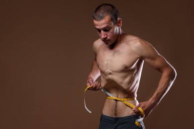 Photo of Anorexic man measuring his waist on beige background. Space for text