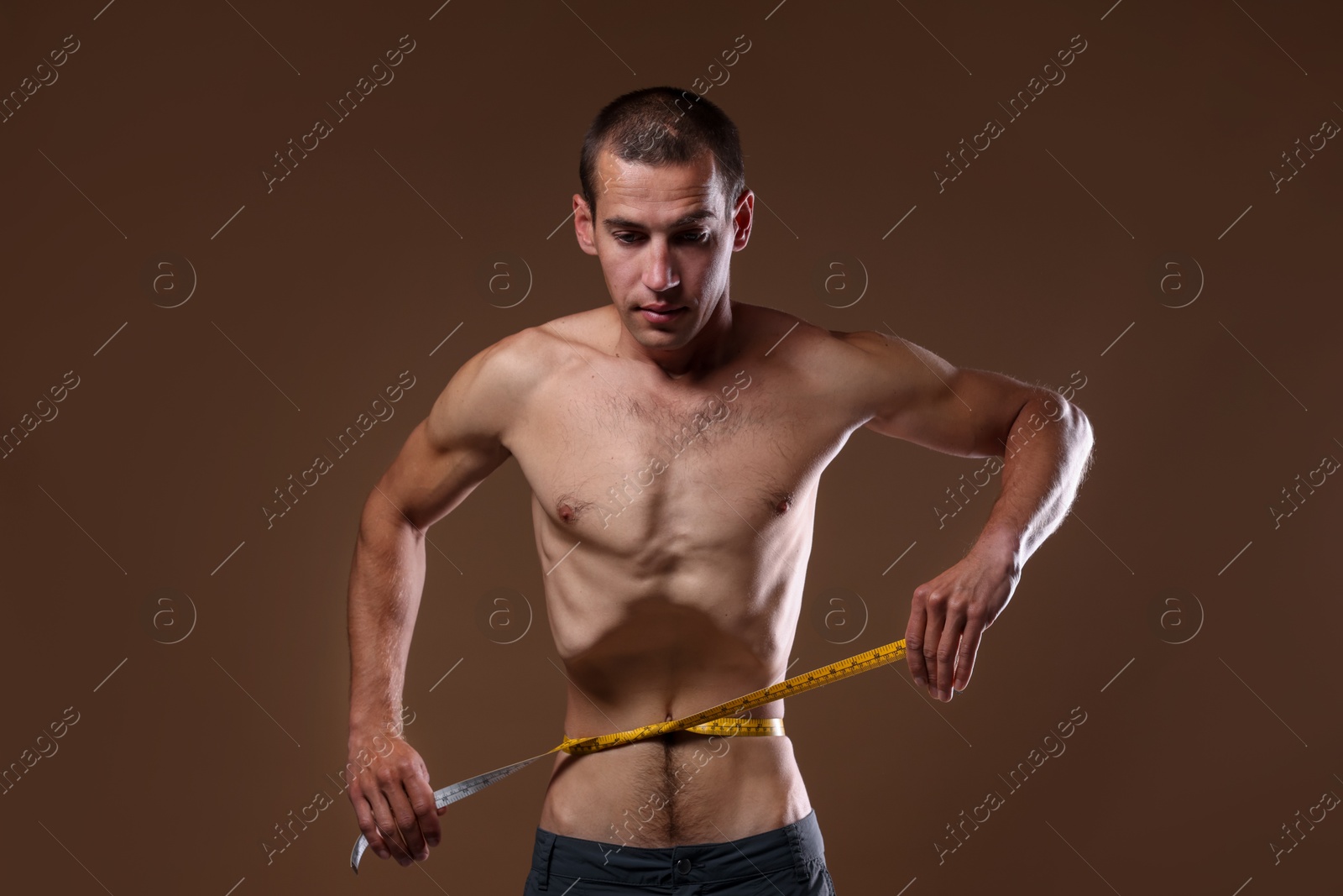 Anorexic man measuring his waist on beige background Photo of Anorexic man measuring his waist on beige background