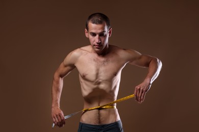 Photo of Anorexic man measuring his waist on beige background