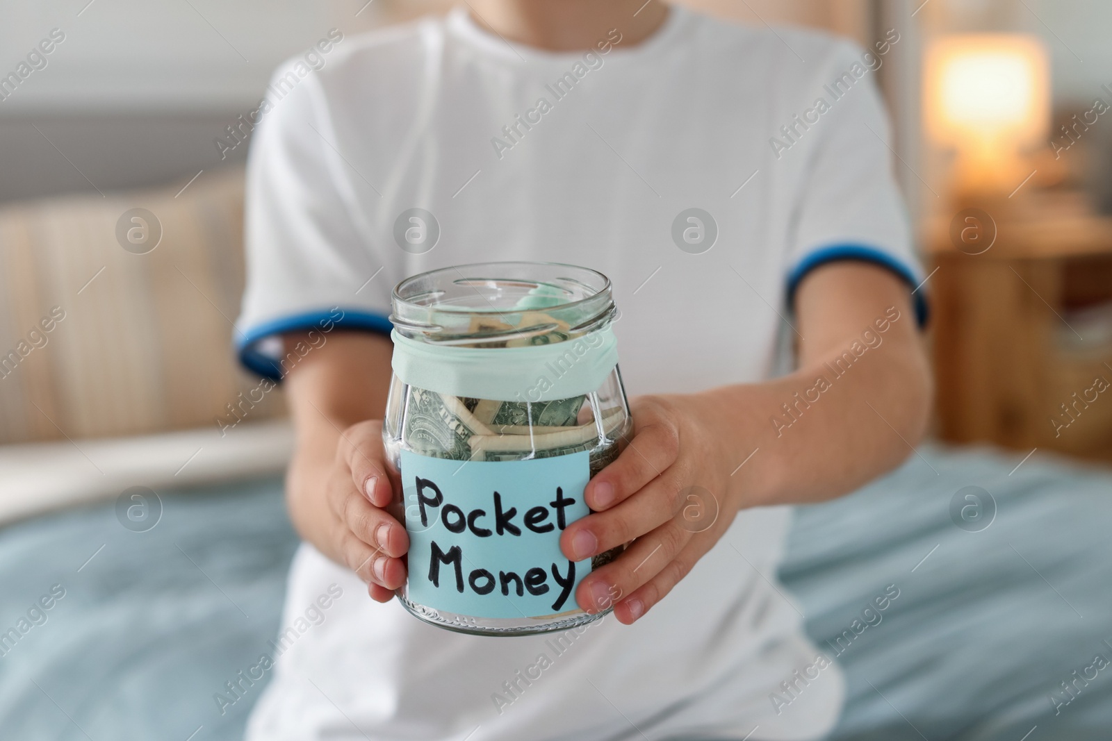 Boy with jar of pocket money on bed at home, closeup Photo of Boy with jar of pocket money on bed at home, closeup