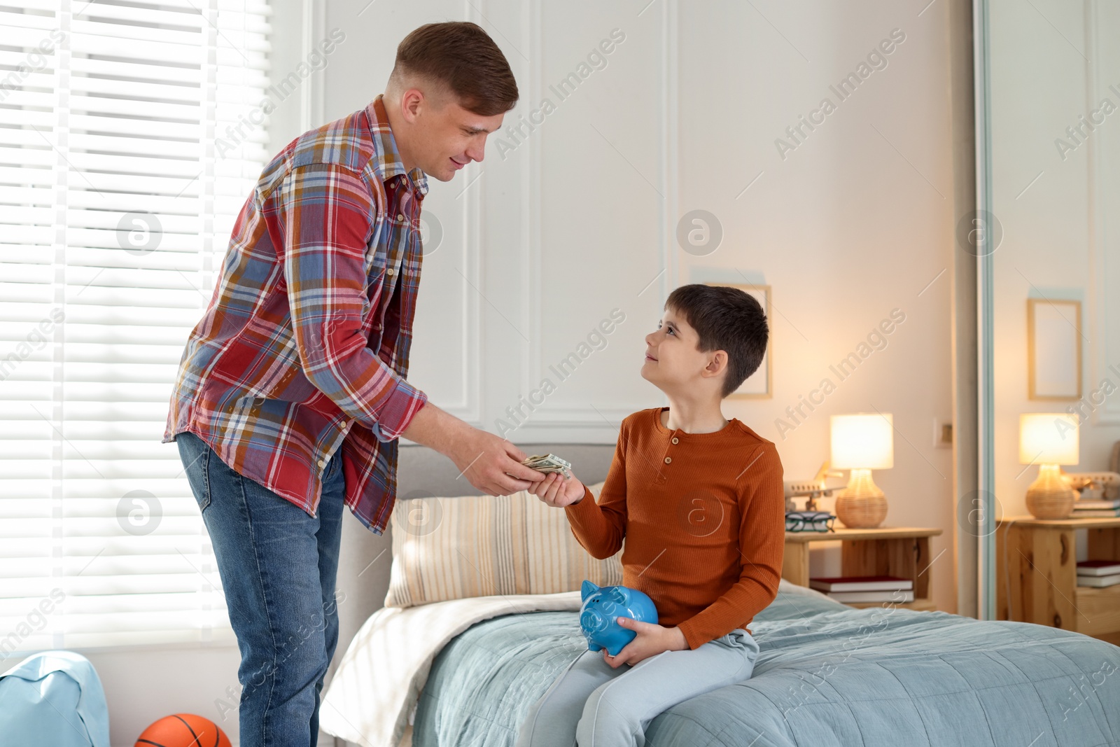 Father giving his son pocket money at home Photo of Father giving his son pocket money at home