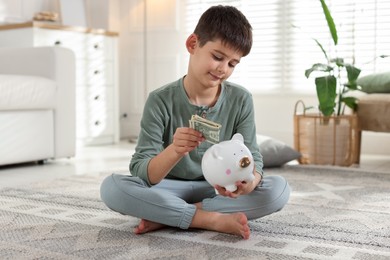 Photo of Boy putting pocket money into piggybank at home