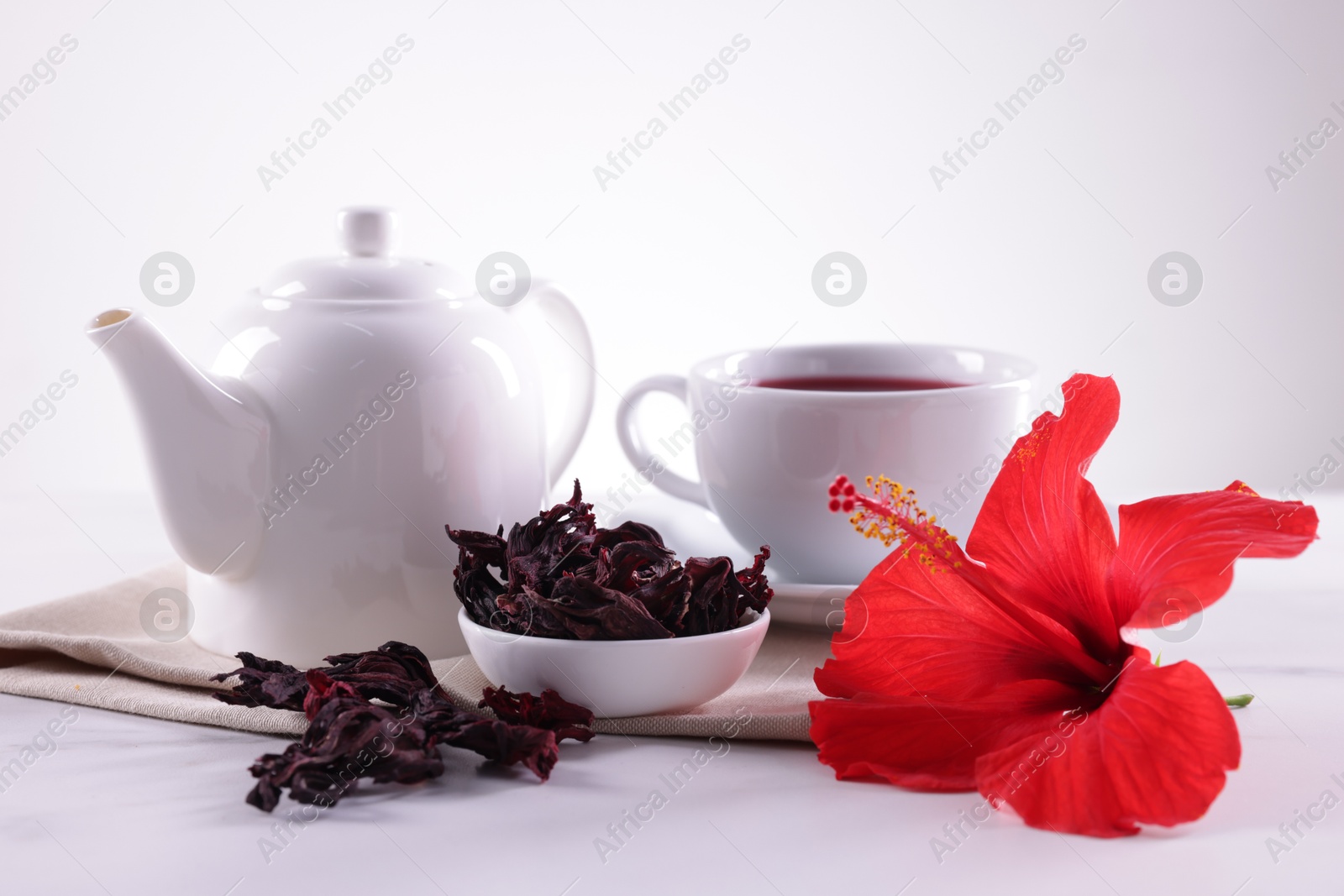 Tasty hibiscus tea, dry roselle sepals and beautiful flower on table against white background, closeup Photo of Tasty hibiscus tea, dry roselle sepals and beautiful flower on table against white background, closeup