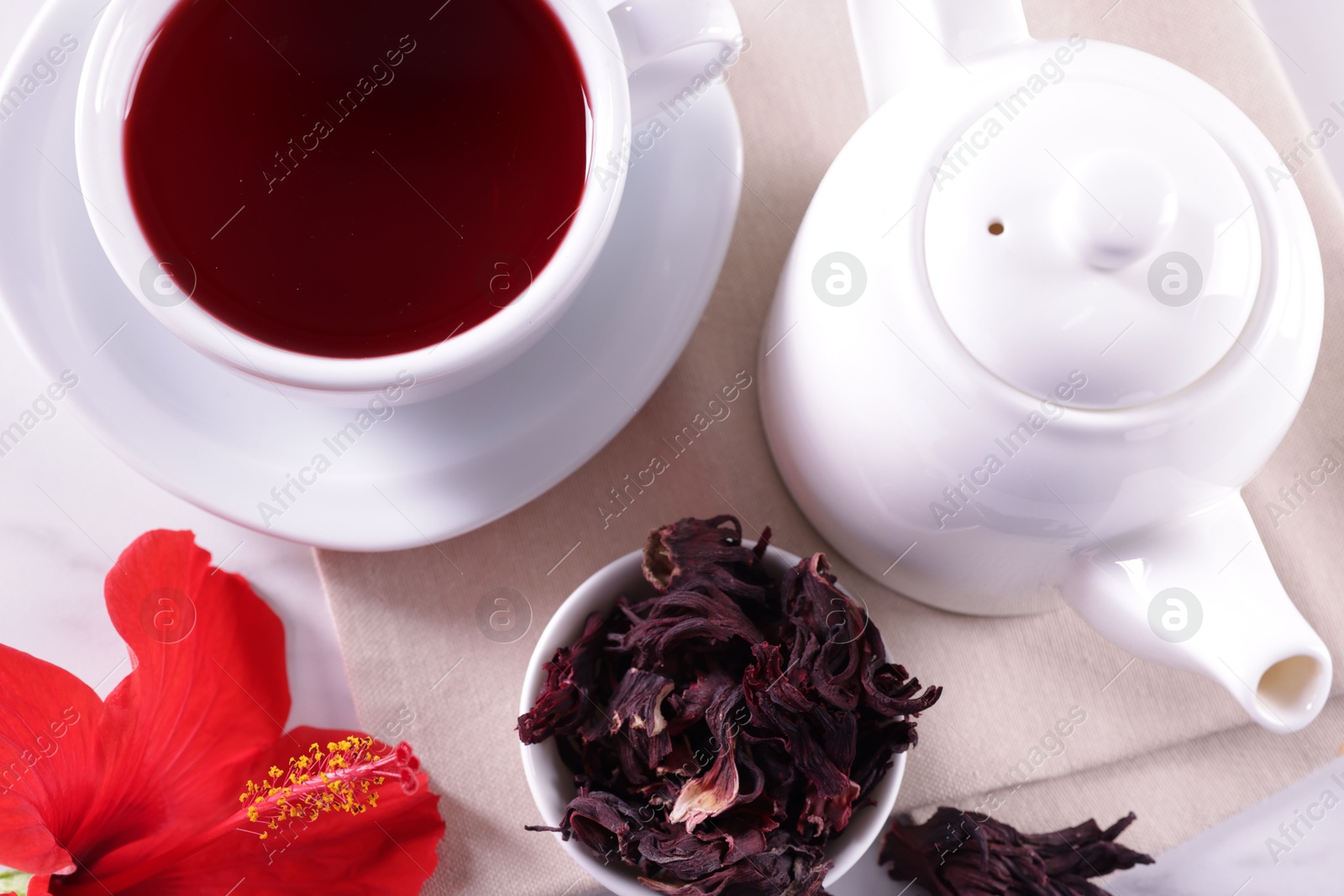 Tasty hibiscus tea, dry roselle sepals and beautiful flower on white table, flat lay Photo of Tasty hibiscus tea, dry roselle sepals and beautiful flower on white table, flat lay