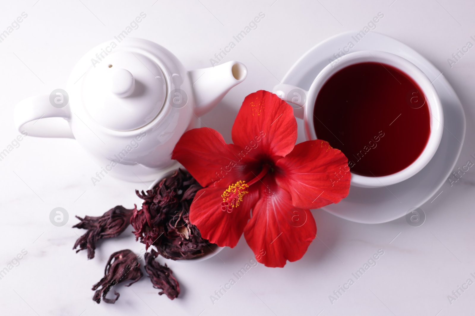 Tasty hibiscus tea, dry roselle sepals and beautiful flower on white table, flat lay Photo of Tasty hibiscus tea, dry roselle sepals and beautiful flower on white table, flat lay
