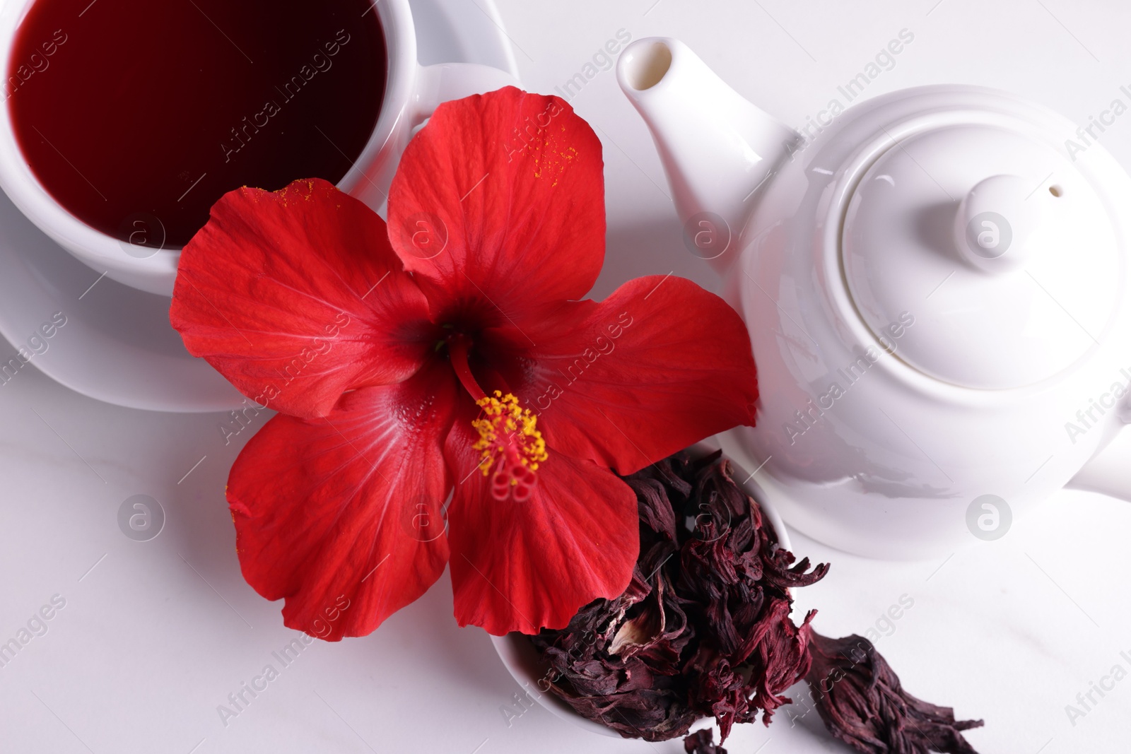 Tasty hibiscus tea, dry roselle sepals and beautiful flower on white table, above view Photo of Tasty hibiscus tea, dry roselle sepals and beautiful flower on white table, above view