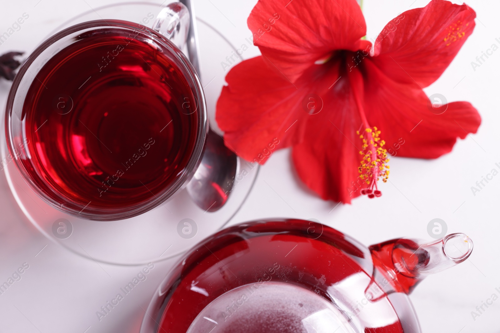Tasty hibiscus tea and beautiful flower on white table, flat lay Photo of Tasty hibiscus tea and beautiful flower on white table, flat lay