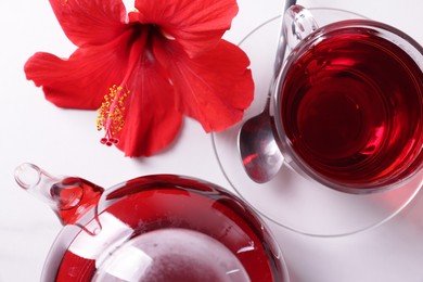 Photo of Tasty hibiscus tea and beautiful flower on white table, flat lay