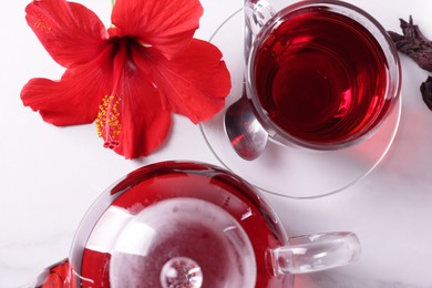 Photo of Tasty hibiscus tea and beautiful flower on white table, flat lay