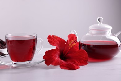 Photo of Tasty hibiscus tea and beautiful flower on white table against grey background