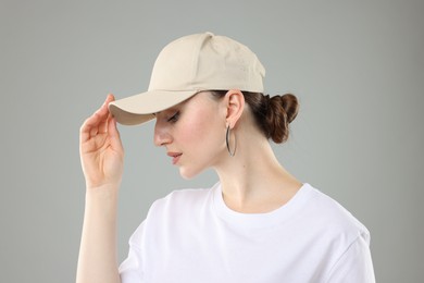 Photo of Beautiful woman in stylish baseball hat on grey background, closeup