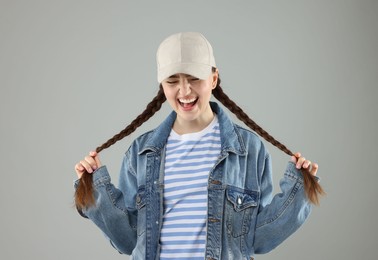 Photo of Happy woman in stylish baseball hat on grey background